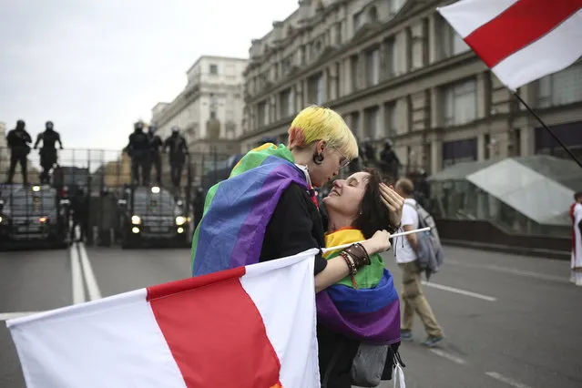 LGBT activists react together, with an old Belarusian national flag, in front of a police barricade blocking a street during an opposition rally to protest the official presidential election results in Minsk, Belarus, Sunday, September 6, 2020. (Photo by TUT.by/AP Photo)