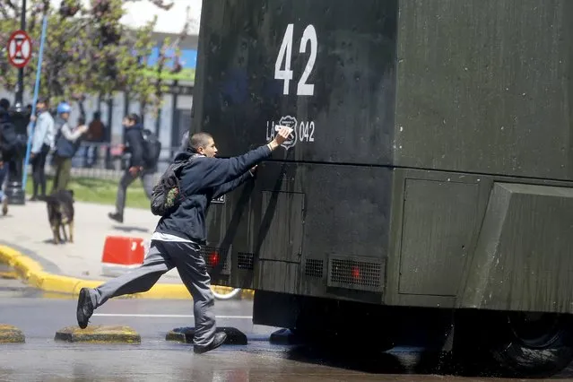 A student protester tries to draw on a riot police vehicle during a demonstration to demand changes in the education system in Santiago, Chile, October 15, 2015. (Photo by Ivan Alvarado/Reuters)