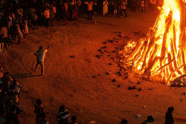 Devotees are performing the largest “Holika Dahan” as part of the Holi festival celebrations in a nearby village near Gandhinagar, the capital of Gujarat, India, on March 24, 2024. They are observing Holika Dahan, which symbolizes the burning of evil, a day before Holi, which is celebrated with color and festivity across the country. The village is maintaining its 700-year-old tradition. A Holi fire, towering at 35 feet and built within a 30-meter circumference using 200 tons of wood, is resulting in flames that soar to impressive heights. (Photo by Saurabh Sirohiya/NurPhoto/Rex Features/Shutterstock)