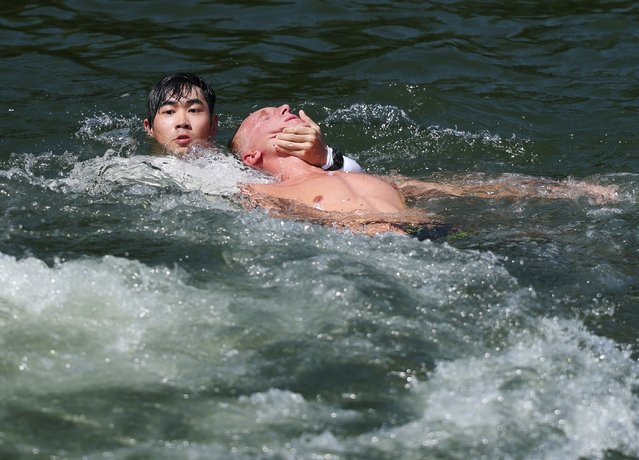 Marc-Antoine Olivier of France (R) is rescued from the water while competing in the Men's 10km Open Water finals at the World Aquatics Championships Singapore 2025 in Singapore, 16 July 2025. (Photo by Fazry Ismail/EPA)