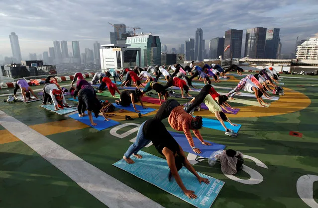 People take part in a sunrise yoga class on the helicopter landing pad on the roof of the Grand Sahid Jaya hotel in Jakarta, Indonesia September 25, 2016. (Photo by Darren Whiteside/Reuters)