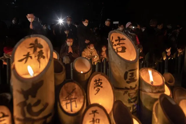 People pray for the victims of the Great Hanshin Earthquake in front of the candle-lit bamboo lanterns, marking the 28th anniversary at Higashi Yuenchi Park on January 17, 2023 in Kobe, Japan. This western Japanese city marked the anniversary of the magnitude 7.3 quake that claimed 6,434 lives after memorials were scaled back in 2021 and 2022 due to the pandemic. (Photo by Buddhika Weerasinghe/Getty Images)