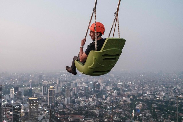 A man rides a swing at the edge of an observatory deck claimed to be Indonesia's highest, at the Thamrin Nine building in Jakarta on July 24, 2025. (Photo by Yasuyoshi Chiba/AFP Photo)
