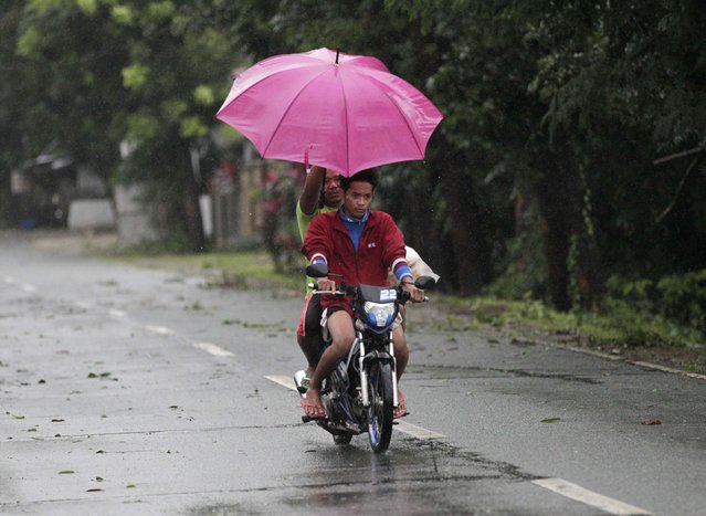 A man uses an umbrella to shield his friend from the rain while riding a motorcycle after strong winds and heavy rains brought on by Typhoon Hagupit battered Laiya town, San Juan city, Batangas province, south of Manila, December 9, 2014. (Photo by Romeo Ranoco/Reuters)