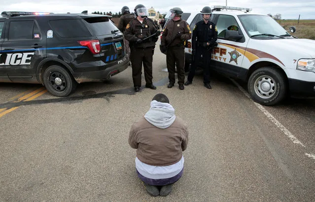 Caro Gonzales of Olympia, Washington, prays in front of police during a protest against the Dakota Access Pipeline between the Standing Rock Reservation and the pipeline route outside the little town of Saint Anthony, North Dakota, U.S., October 5, 2016. (Photo by Terray Sylvester/Reuters)