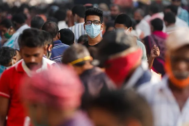 A man wearing a protective mask is seen among people at a crowded market amidst the spread of the coronavirus disease (COVID-19) in Mumbai, India, October 29, 2020. (Photo by Francis Mascarenhas/Reuters)