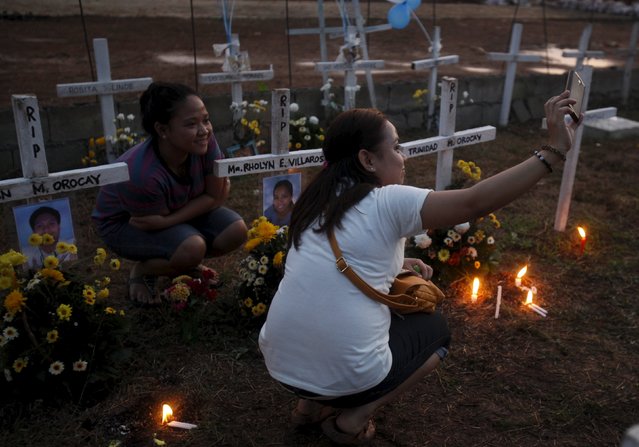 Residents take a "selfie" at the graves of their loved ones at a mass grave for Typhoon Haiyan victims on All Saints Day in Tacloban city in central Philippines November 1, 2015, and ahead of the second anniversary of the devastating typhoon that killed more than 6,000 people in central Philippines. (Photo by Lorgina Minguito/Reuters)