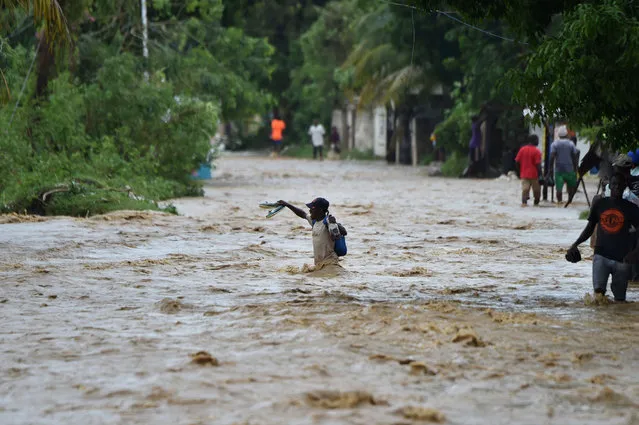 People try to cross the overflowing La Rouyonne river in the commune of Leogane, south of Port-au-Prince, October 5, 2016. Haiti and the eastern tip of Cuba – blasted by Matthew on October 4, 2016 – began the messy and probably grim task of assessing the storm's toll. Matthew hit them as a Category Four hurricane but has since been downgraded to three, on a scale of five, by the US National Hurricane Center. (Photo by Hector Retamal/AFP Photo)