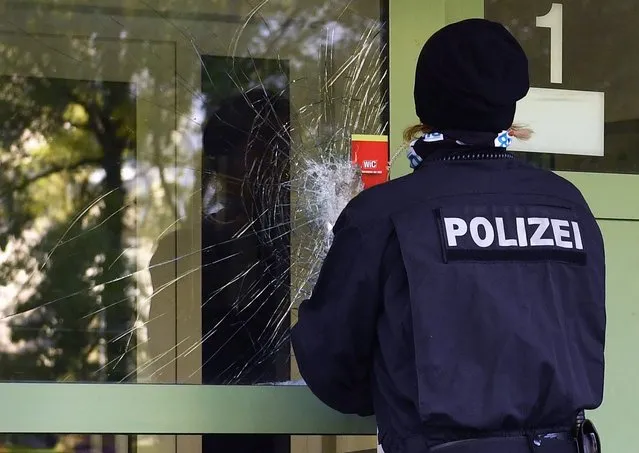 A police officer seals the damaged front door of a residential property in a housing estate in the Yorck area of Chemnitz, Germany, 09 October 2016. Special police forces raided a second apartment in the area in pursuit of terror suspect Jaber al-Bakr. The apartment was one of a number of contact addresses found amongst 22-year-old's possessions. The other addresses are currently being investigated. (Photo by Hendrik Schmidt/EPA)