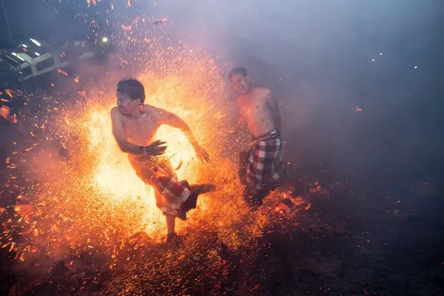 Balinese men hit each other using burn coconut husks during the fire fight ritual called Mesabatan Api on March 21, 2023 at traditional sub village of Nagi, in Gianyar, Bali, Indonesia. The mesabatan api ritual is held annually on the eve of Nyepi, the Hindu Day of Silence, the Balinese Caka New Year, and only takes place in Pakraman Nagi village in Gianyar regency, around 30 kilometers from Denpasar. (Photo by Agung Parameswara/Getty Images)