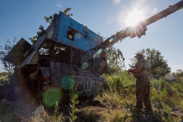 A Ukrainian serviceman of the 22nd Separate Mechanised Brigade stands next to a Russian T-62 Soviet main battle tank crafted with anti-drone protection that was recently captured by his unit, amid Russia's attack on Ukraine, at an undisclosed location in Donetsk region, Ukraine on June 19, 2024. (Photo by Alina Smutko/Reuters)