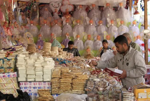 People buy traditional sweets for children to celebrate the birthday of prophet Muhammad, also known as “mawlid al nabi”, which will fall next week, in a makeshift tent in Cairo, December 30, 2014. (Photo by Mohamed Abd El Ghany/Reuters)