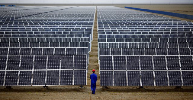 A worker inspects solar panels at a solar Dunhuang, 950km (590 miles) northwest of Lanzhou, Gansu Province in this September 16, 2013 file photo. (Photo by Carlos Barria/Reuters)