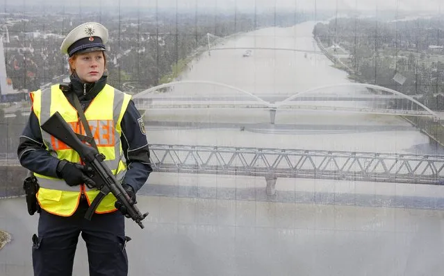 A German police officer stands in front of a poster with a picture of the Rhein river as she takes part in a security control at the French-German border in Strasbourg, France, November 28, 2015, as security measures on the French borders is reinforced after recent deadly attacks in Paris and ahead of the upcoming COP21 World Climate Summit. (Photo by Vincent Kessler/Reuters)