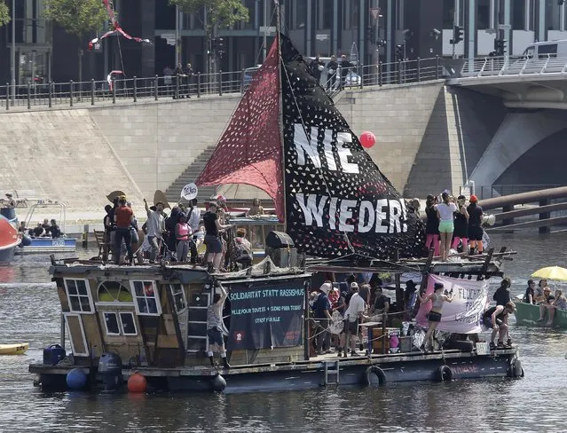 Activists protest against racism on a ship on the Spree river in Berlin, Germany, Sunday, May 27, 2018. The AfD that swept into Parliament last year on a wave of anti-migrant sentiment is staging a march Sunday through the heart of Berlin to protest against the government. (Photo by Markus Schreiber/AP Photo)