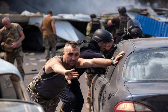 Emergency workers and soldiers push a damaged cars after a Russian missile hit a supermarket in Kostiantynivka, Donetsk region, Ukraine, Friday, August 9, 2024. (Photo by Iryna Rybakova/AP Photo)