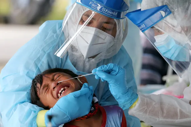 Medical workers collect a swab sample from a boy to be tested for the coronavirus disease (COVID-19) in Klang, Malaysia on December 2, 2020. (Photo by Lim Huey Teng/Reuters)