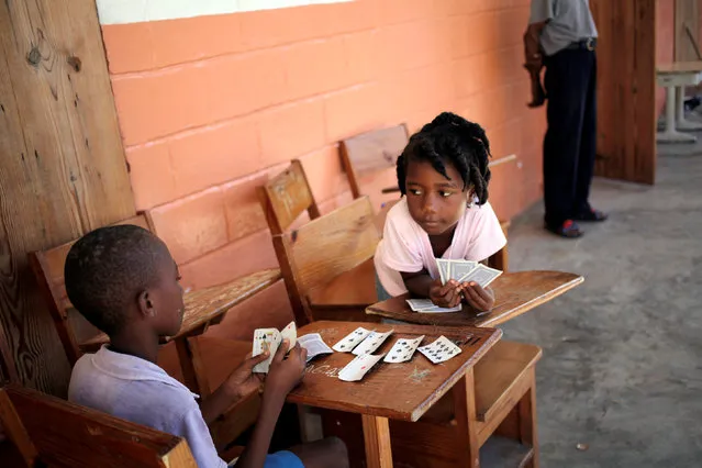 Two kids play cards at the school Inmaculate Conception after Hurricane Matthew in Les Anglais, Haiti, October 12, 2016. (Photo by Andres Martinez Casares/Reuters)