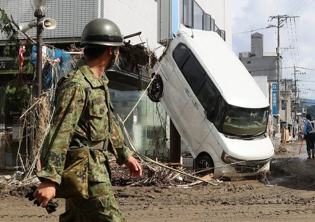 An officer walks psat a damaged car in Hitoyoshi, in Kumamoto Prefecture on July 8, 2020. Japan will deploy more troops to search for survivors of devastating floods and landslides that have killed at least 52 people in the southwest of the country, Prime Minister Shinzo Abe pledged. (Photo by JIJI Press/AFP Photo/Stringer)