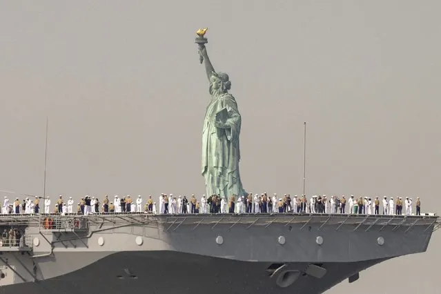 U.S. Sailors and Marines stand on the deck of the USS Wasp, an amphibious assault ship, as it passes the Statue of Liberty during Fleet Week on Wednesday, May 24, 2023 in New York. (Photo by Yuki Iwamura/AP Photo)