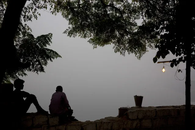 Indians sit on the banks of the river Yamuna engulfed with smog in New Delhi, India, Sunday, November 6, 2016. The Delhi government has ordered that all city schools be shut, construction activity halted and all roads be doused with water as crippling air pollution has engulfed the Indian capital. The city, one of the world's dirtiest, has seen the levels of PM2.5 soar to over 900 microgram per cubic meter on Saturday, more than 90 times the level considered safe by the World Health Organization and 15 times the Indian government's norms. (Photo by Manish Swarup/AP Photo)