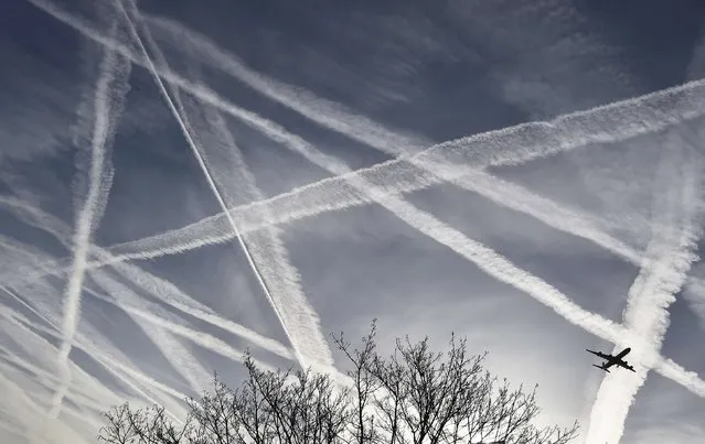 A passenger plane flies through aircraft contrails in the skies near Heathrow Airport in London, Britain, April 12, 2015. (Photo by Toby Melville/Reuters)