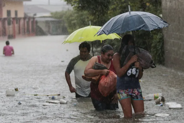 Residents wade through a flooded road carrying some belongings, in Progreso Yoro, Honduras, Wednesday, November 4, 2020. Eta weakened from the Category 4 hurricane to a tropical storm after lashing the Caribbean coast for much of Tuesday, its floodwaters isolating already remote communities and setting off deadly landslides. (Photo by Delmer Martinez/AP Photo)