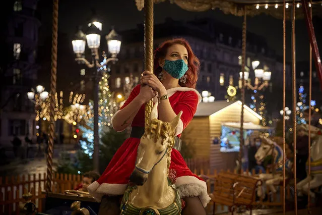 A Parisian enjoys the free traditional carousel at the Christmas Village at Hotel de Ville in Paris, as France prepares to exit from strict lockdown on Tuesday in time for Christmas on December 14, 2020 in Paris, France. France is trading its second nationwide lockdown for a more lenient curfew despite Covid-19 hospitalizations rising slightly in recent days, but are still within the range deemed acceptable for easing the restrictions imposed on October 30. However, bars, restaurants, museums, theatres and cinemas must remain shut until least the first week of January. (Photo by Kiran Ridley/Getty Images)