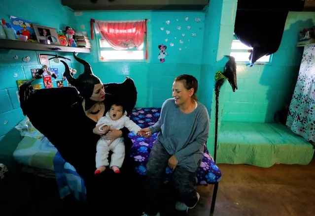 Gabriela Ibanez, a 35-year-old inmate, talks in her prison cell with a volunteer of the so-called Hero Club (Club de Heroes), Fernanda Ausejo, who impersonates Maleficent, as she holds her daughter, Teresita, at the 33rd prison in Los Hornos during a visit as part of a wider program for vulnerable minors, on the outskirts of Buenos Aires, Argentina on April 30, 2022. (Photo by Agustin Marcarian/Reuters)