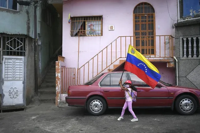 A girl flies a Venezuelan flag during the anniversary of his 1992 failed coup attempt by the late President Hugo Chavez at the 23 de Enero neighborhood of Caracas, Venezuela, Thursday, February 4, 2021. Chavez led the unsuccessful coup against President Carlos Andres Perez in 1992 for which he was imprisoned. In 1998 he was elected president and remained in power until he died of cancer in 2013. (Photo by Matias Delacroix/AP Photo)