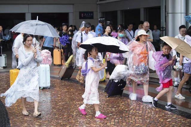 In this photo released by Xinhua News Agency, tourists walk in the rain as Typhoon Talim approaches in Macao in southern China on Monday, July 17, 2023. Schools and the stock market were closed in Hong Kong on Monday as Typhoon Talim sideswiped the city and headed toward landfall on the Chinese mainland and the island province of Hainan. (Photo by Cheong Kam Ka/Xinhua via AP Photo)