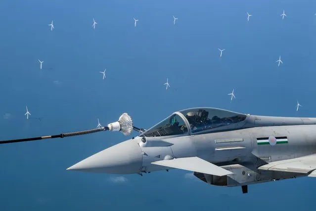 Wind turbines are seen in the distance as an  RAF Typhoon fighter jet is refuelled in-flight over the North Sea, from a Voyager aircraft flying on a 43% blend of sustainable fuel on April 17, 2023 in flight – Region EMEA. The RAF have been experimenting with sustainable aviation fuel (SAF) since the first RAF Voyager flight fuelled by 100% SAF in 2022. Current regulations permit a maximum of a 50:50 blend of sustainable aviation fuel and traditional fossil fuels. As the fuel is currently two to three times more expensive than the traditional option, the RAF hopes that by demonstrating it's belief in more environmentally-friendly fuel, the uptake will increase, subsequently driving the price down. (Photo by Leon Neal/Getty Images)