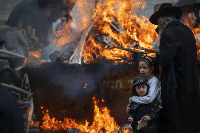 Ultra-Orthodox Jewish men and children burn leavened items in final preparation for the Passover holiday in the ultra-Orthodox Jewish town of Bnei Brak, near Tel Aviv, Israel, Friday, March 26, 2021. Jews are forbidden to eat leavened foodstuffs during the Passover holiday that celebrates the biblical story of the Israelites' escape from slavery and exodus from Egypt. (Photo by Oded Balilty/AP Photo)