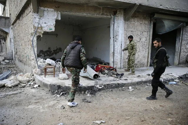 Syrian army soldiers check the body of a militant fighter in the east Aleppo neighborhood of Tariq al-Bab, Syria, Saturday, December 3, 2016. Tariq al-Bab was captured by Syrian government forces on Friday. (Photo by Hassan Ammar/AP Photo)