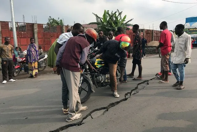 People look at a crack on the road caused by earth tremors as aftershocks following the eruption of Mount Nyiragongo volcano near Goma, in the Democratic Republic of Congo on May 26, 2021. (Photo by Djaffar Al Katanty/Reuters)