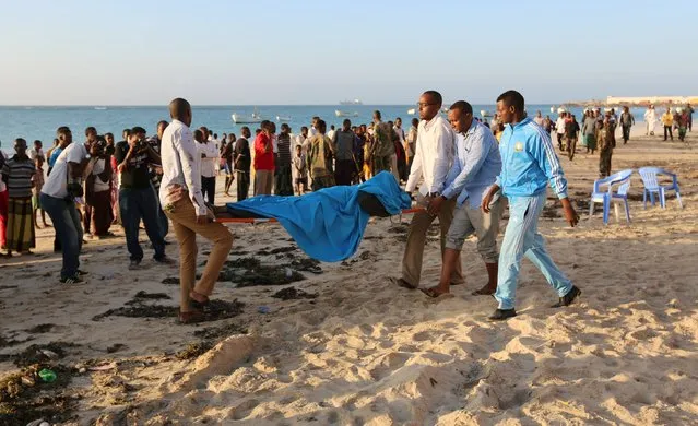 Relatives carry the body of their kin killed in an attack at beachside restaurant Beach View Cafe, on Lido beach in Somalia's capital Mogadishu, January 22, 2016. (Photo by Feisal Omar/Reuters)
