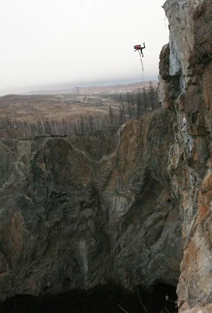 A member of the “Exit Point” amateur rope-jumping group takes a rope jump from a 120-metre high rock down to a man-made crater called “Tuimsky Proval” outside the town of Tuim in Khakassia region, Russia, on Oktober 22, 2013. (Photo by Ilya Naymushin/Reuters)