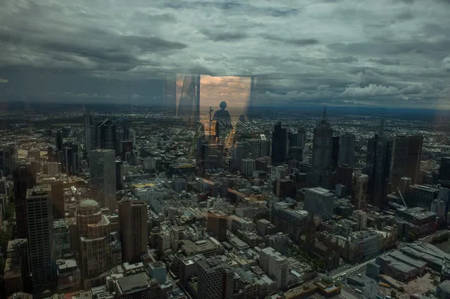 A picture made available 01 February 2016 shows a visitor reflected in glass as they observe Melbourne from Eureka Skydeck 88 tower, Australia, 31 January 2016. At 300 metres, Eureka Skydeck tower is the highest public viewing platform in the Southern Hemisphere. The tower itself is also the world's tallest residential structure. (Photo by Filip Singer/EPA)