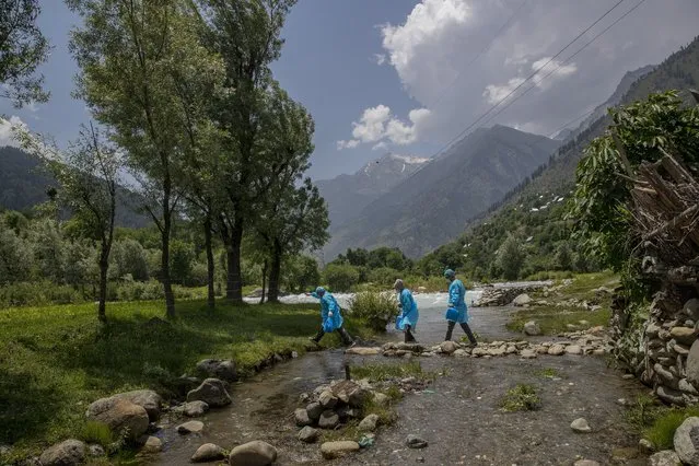 Healthcare workers Masrat Farid and her colleagues cross a stream near river Sind to reach villages on the upper reaches during a COVID-19 vaccination drive in Gagangeer, northeast of Srinagar, Indian controlled Kashmir on June 22, 2021. (Photo by Dar Yasin/AP Photo)