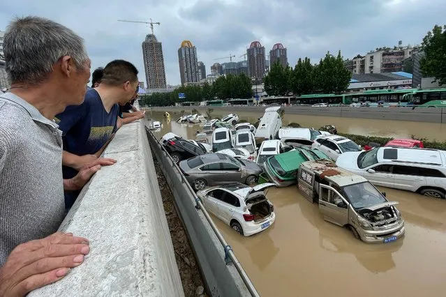 People look out at cars sitting in floodwaters after heavy rains hit the city of Zhengzhou in China's central Henan province on July 21, 2021. (Photo by AFP Photo/China Stringer Network)