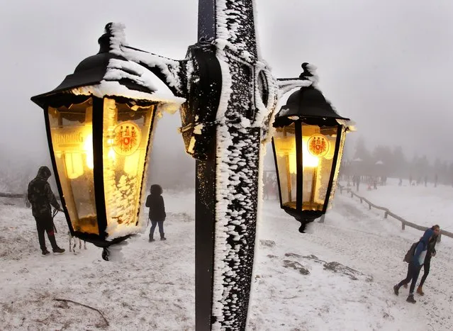 Lamps of a restaurant shine as trippers walk by in thick fog on top of the 880 m high Feldberg mountain near Frankfurt, Germany, Monday, January 2, 2017. (Photo by Michael Probst/AP Photo)