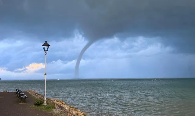 A tornado, or waterspout, is witnessed over the Veronese part of the Lake Garda, northern Italy, 08 September 2022. Although the water tornados mostly occour in tropical and subtropical areas they are also possible under certain weather conditions over larger lakes and standing waters in Europe and other parts of the globe. (Photo by Sandro Benedetti/EPA/EFE)