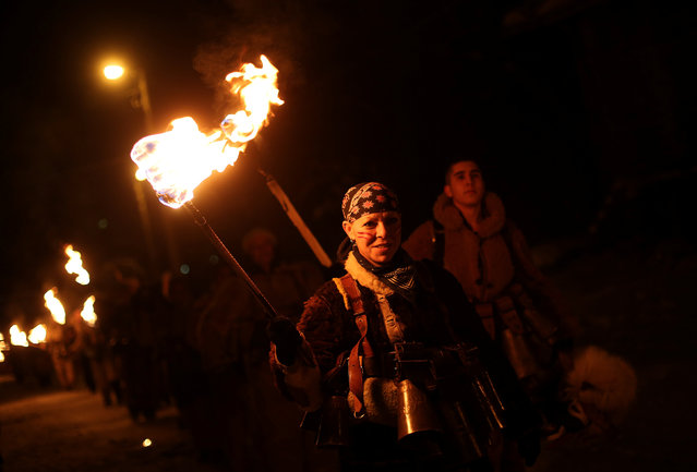 A woman dressed in a costume made of animal fur, called “kuker”, carries a torch during a festival in the town of Batanovtsi, Bulgaria January 13, 2017. (Photo by Stoyan Nenov/Reuters)