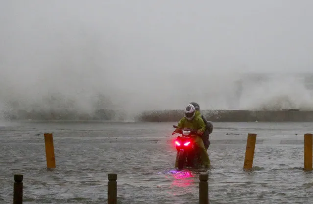 A motorist braves the rain and strong winds brought about by Typhoon Mangkhut which barreled into northeastern Philippines before dawn Saturday, September 15, 2018 in Manila, Philippines. (Photo by Bullit Marquez/AP Photo)