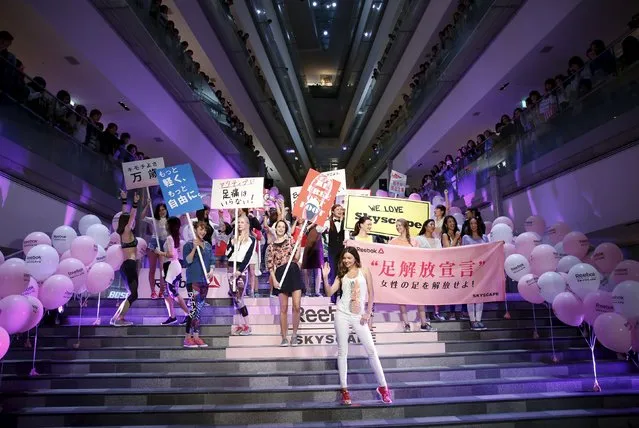 Australian model Miranda Kerr (front) leads women holding placards and a banner (R), which reads “Women be freed from bad-fitting shoes”, during a promotional event for the Reebok Skyscape shoes series at the Omotesando Hills in Tokyo April 15, 2015. (Photo by Issei Kato/Reuters)