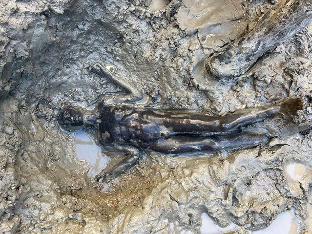 A handout photo made available by the University for Foreigners of Siena (Universita per Stranieri di Siena) shows a statue (praying ephebe) emerging from the mud during the discovery of a votive deposit in the excavations of San Casciano dei Bagni, Tuscany, Italy, 07 November 2022. Protected for 2,300 years from the mud and boiling water of the sacred basins, a never-before-seen votive deposit has re-emerged from the excavations of San Casciano dei Bagni, in Tuscany, with over 24 bronze statues of refined workmanship, five of which almost one meter high, all intact and in good condition. (Photo by Jacopo Tabolli/Universita per Stranieri di Siena/EPA/EFE)