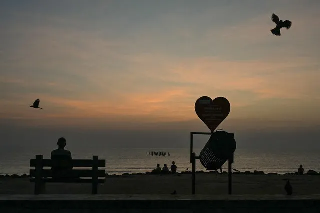 A man sitting on a bench overlooking the Bay of Bengal waits for the sunrise in Puducherry on January 17, 2024. (Photo by Arun Sankar/AFP Photo)