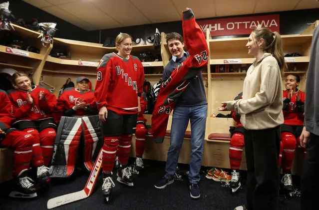 Canada's Prime Minister Justin Trudeau puts on an Ottawa team jersey as he speaks with Professional Women's Hockey League (PWHL) players in the locker room before their Ottawa vs Boston game in Ottawa, Ontario, Canada on January 24, 2024. (Photo by Patrick Doyle/Reuters)