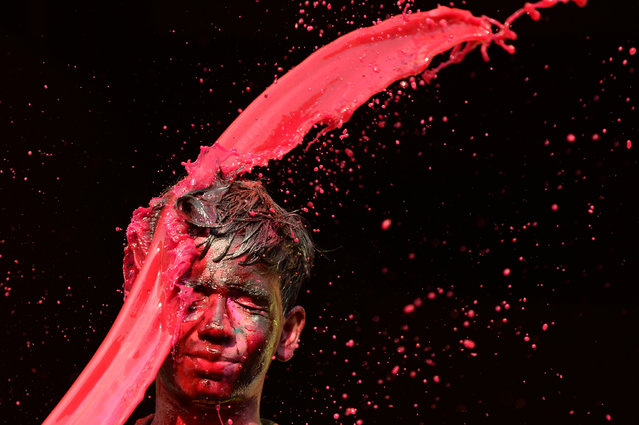 An Indian raveller gestures as he is thrown coloured water by another during Holi festival celebrations in Chennai on March 21, 2019. Holi, the popular Hindu spring festival of colours is observed in India and across countries at the end of the winter season on the last full moon of the lunar month. (Photo by Arun Sankar/AFP Photo)