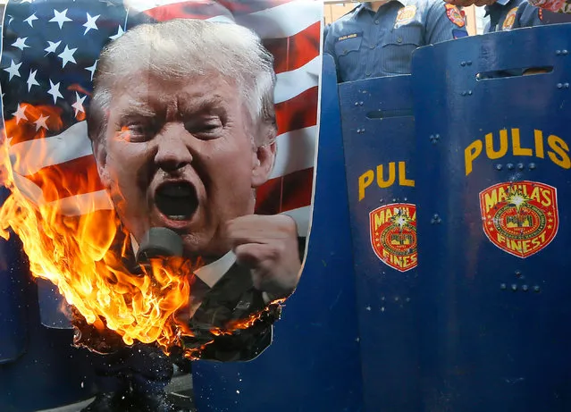 Protesters burn a portrait of U.S. President Donald Trump in front of riot police during a rally in front of the U.S. Embassy Saturday, February 4, 2017 in Manila, Philippines. The protesters scored Trump on his anti-immigration stance. (Photo by Bullit Marquez/AP Photo)